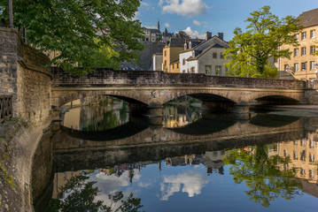 Fototapeta na wymiar Stone bridge reflecting in the Alzette river in the city of Luxe