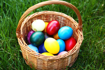 Basket with coloured Easter eggs on green grass