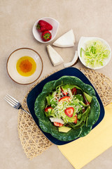 light salad with avocado, coconut, strawberry and rocket