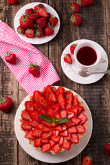 Tart with strawberries and whipped cream on wooden vintage table