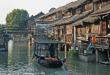 Shanghai, Wuzhen historic scenic town old houses, bridge and boat for tourists along a canal. 