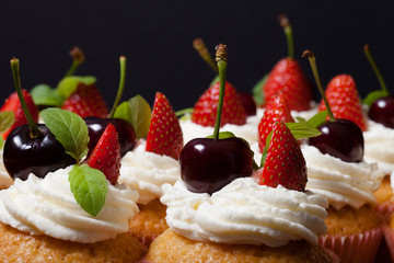 Fresh cupcakes with cream and berries. Shallow depth of field. S