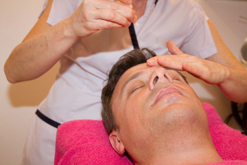 Obraz na płótnie Canvas Man getting face and head massage in the spa centre