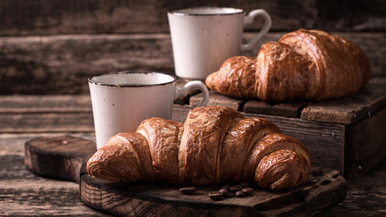 Breakfast with coffee and croissants on wooden vintage table