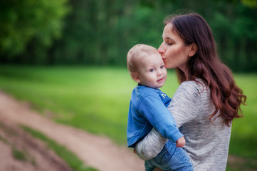 Fototapeta premium brunette mom is holding in her arms her little boy and kissing him