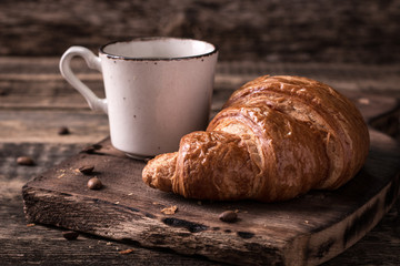 Breakfast with coffee and croissants on wooden vintage table