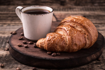 Breakfast with coffee and croissants on wooden vintage table
