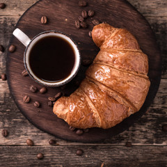 Breakfast with coffee and croissants on wooden vintage table