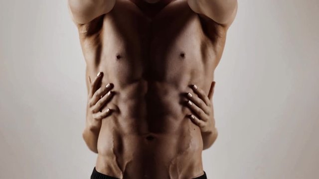 Hands of young woman touching athletic torso with abs of man. Graded