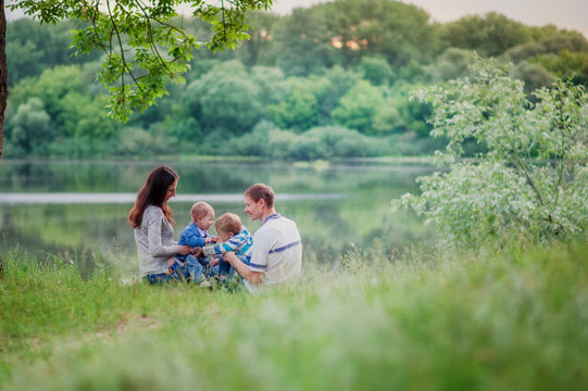 a happily married couple with two children sitting on the Bank of the river, back