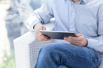 businessman sitting in summer cafe and holding a computer tablet