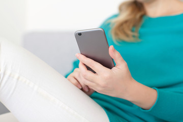 woman sitting on the sofa and holding a mobile phone