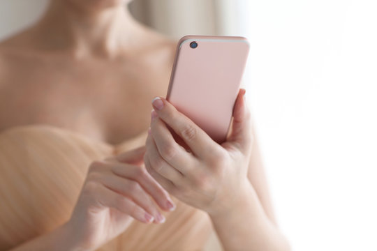 The woman in a beautiful tender dress holding pink phone