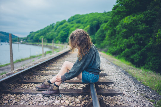 Young woman sitting on railroad tracks
