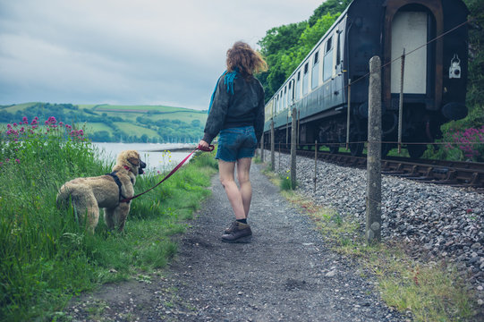 Young woman walking dog by railroad tracks