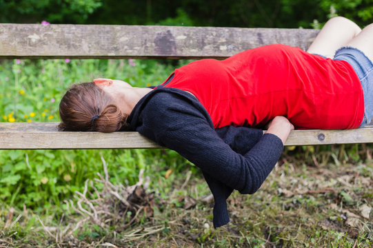 Pregnant woman sleeping on bench in forest