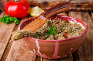 Babaganoush with tomatoes, cucumber and parsley - arabian eggplant dish or salad on wooden background. Selective focus