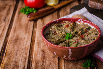 Babaganoush with tomatoes, cucumber and parsley - arabian eggplant dish or salad on wooden background. Selective focus