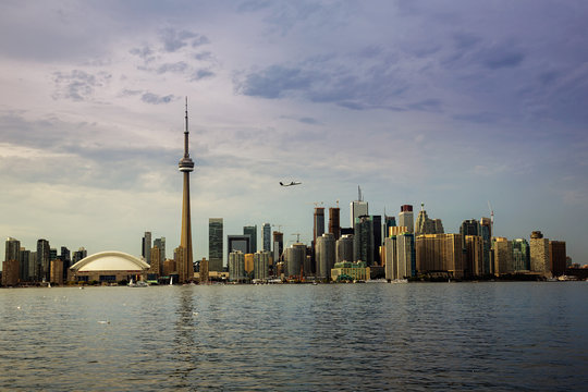 The Toronto skyline, seen from Toronto Island with a passenger jet taking off over the city.