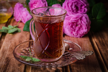 Turkish tea in a glass cup on wooden background with roses. Ramadan food. Selective focus
