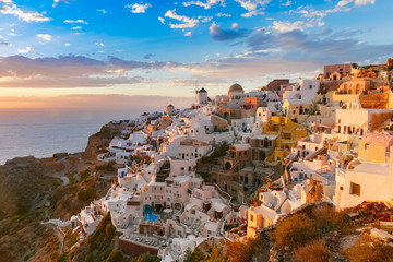 Fototapeta na wymiar Picturesque view, Old Town of Oia or Ia on the island Santorini, white houses, windmills and church with blue domes at sunset, Greece
