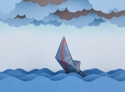 Paper boat is sinking into paper sea. Paper waves and clouds. Co