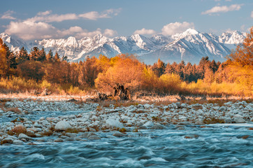 Obraz premium Beautiful autumn panorama over Bialka river to snowy Tatra mountains, Poland - focus on water and stones