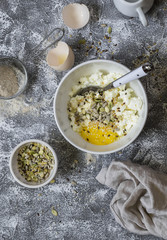 Ingredients for cooking whole grain multi seed bread - whole wheat flour, eggs, ricotta cheese, seeds, on a grey stone background. Baking background