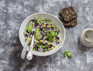 Fresh vegetable salad with white and red cabbage, cucumber, radish and cilantro in a ceramic dish on a stone texture. Healthy vegetarian food.