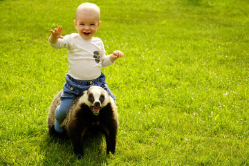 small boy sits astride a scarecrow badger