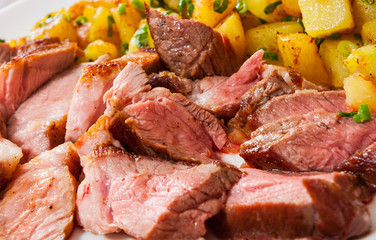 Sliced medium rare grilled Steak Ribeye with potato in a plate on wooden table