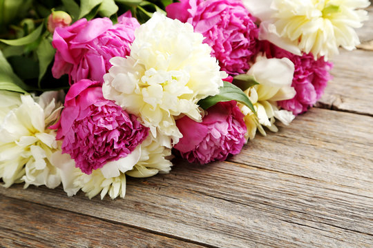 Bouquet of pink and white peony flowers on wooden table