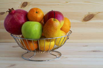 Fresh exotic fruits in a basket on a wooden background.