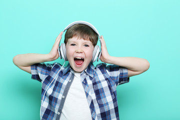 Portrait of young boy with headphones on mint background