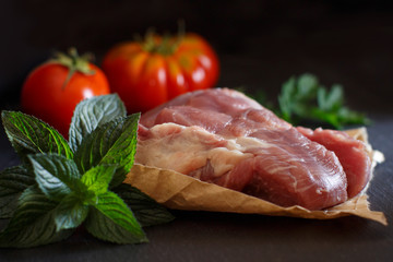 Slice of raw turkey steak with herbs and tomatoes