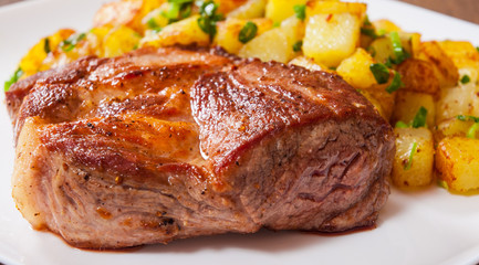 grilled meat fillet steak with fried potato in a plate on wooden table