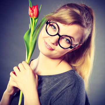 Nerdy girl sniffing flower.