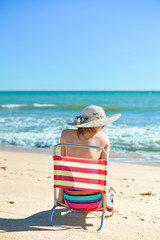 Back view of female sunbathe relaxing, sunny summer beach outdoors vacation