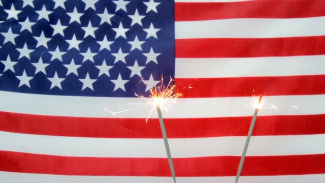 Sparklers burning against American flag.