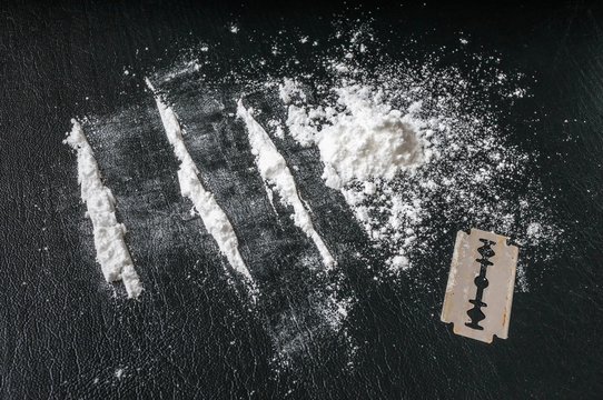 Cocaine white powder in lines and razor. Narcotics concept.