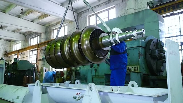 worker lathe operator in a factory transportation rotor parts