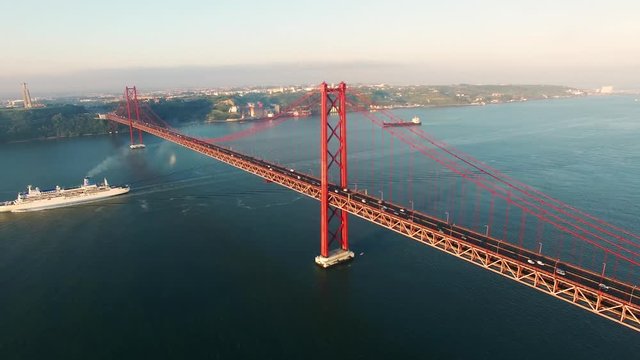 cruise ship under Bridge Ponte 25 de Abril over the Tagus river in Lisbon, Portugal aerial view