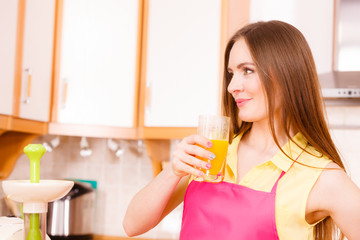 Woman in kitchen drinking fresh orange juice