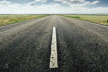asphalt road with a marking leaving afar on a summer day. Close-up