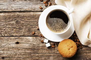 Close-up of coffee cup with roasted coffee beans on wooden backg