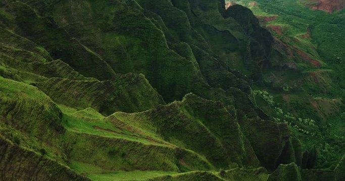 Aerial view flying over jungle mountain peaks revealing tropical coastline, Na Pali coast Kauai