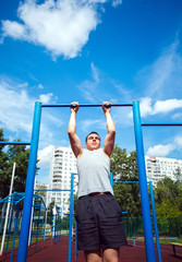 Muscular man doing pull-ups on horizontal bar