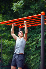 Obraz premium Muscular man doing pull-ups on horizontal bar