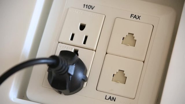 Plugging an electrical cable into multifunctional outlet with lan, fax, 110 and 220 plugs