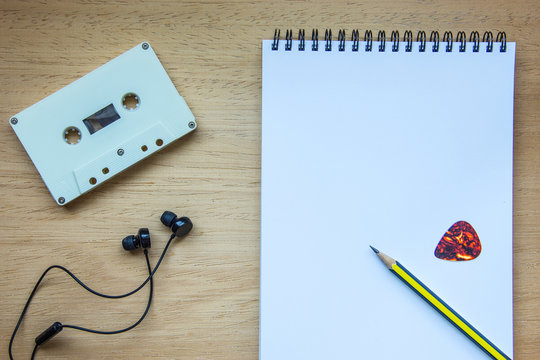 Cassette ,headphones and blank notebook on wood for songwriter b